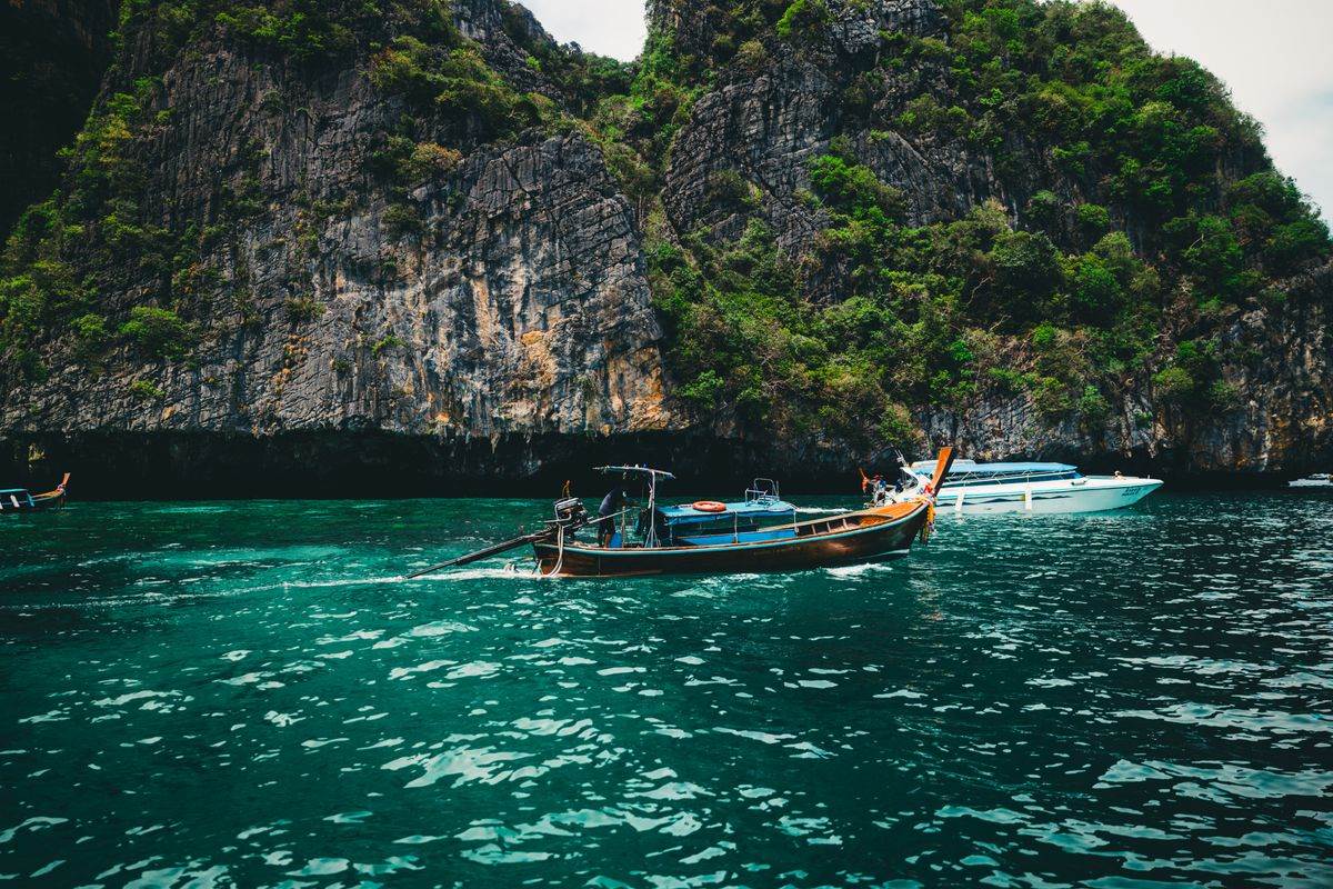 Longtail boat below limestone cliffs on the Andaman Sea