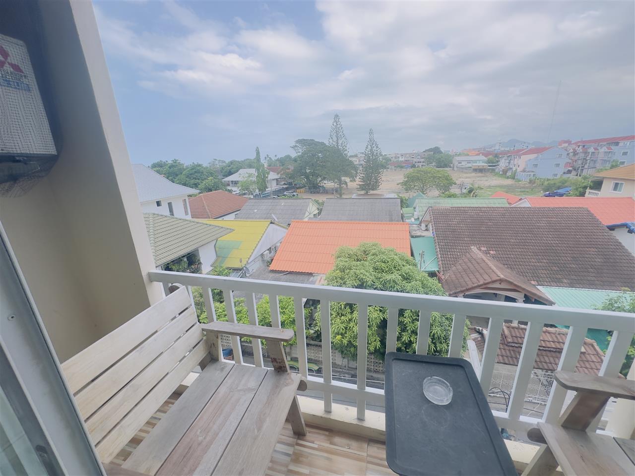 Hotel balcony with wooden chairs and a view over rooftops