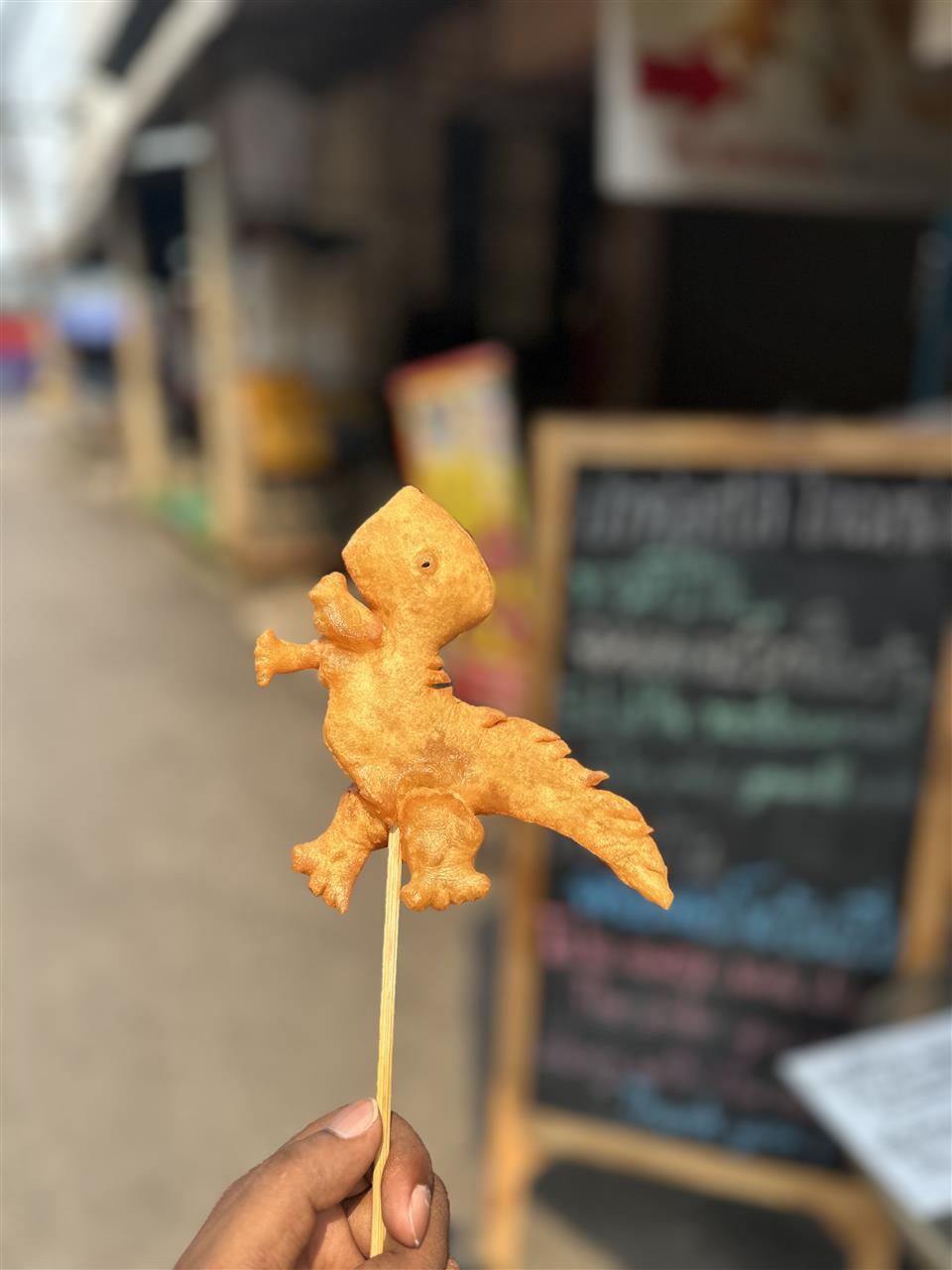 Fried dinosaur-shaped snack on a stick from a Thai street stall